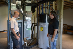 Homeowner Joe Johnson shows Dawson PPD Energy Services Specialist Bobby Johnson (left) the connections between his geothermal heat pump and heat pump water heater.