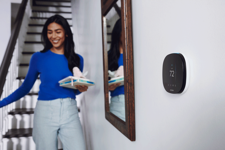 Woman walks by smart thermostat