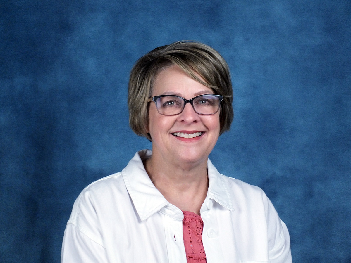 A headshot of Nancy Davenport, retired Dawson PPD Accountant. Woman wearing glasses with white jacket.