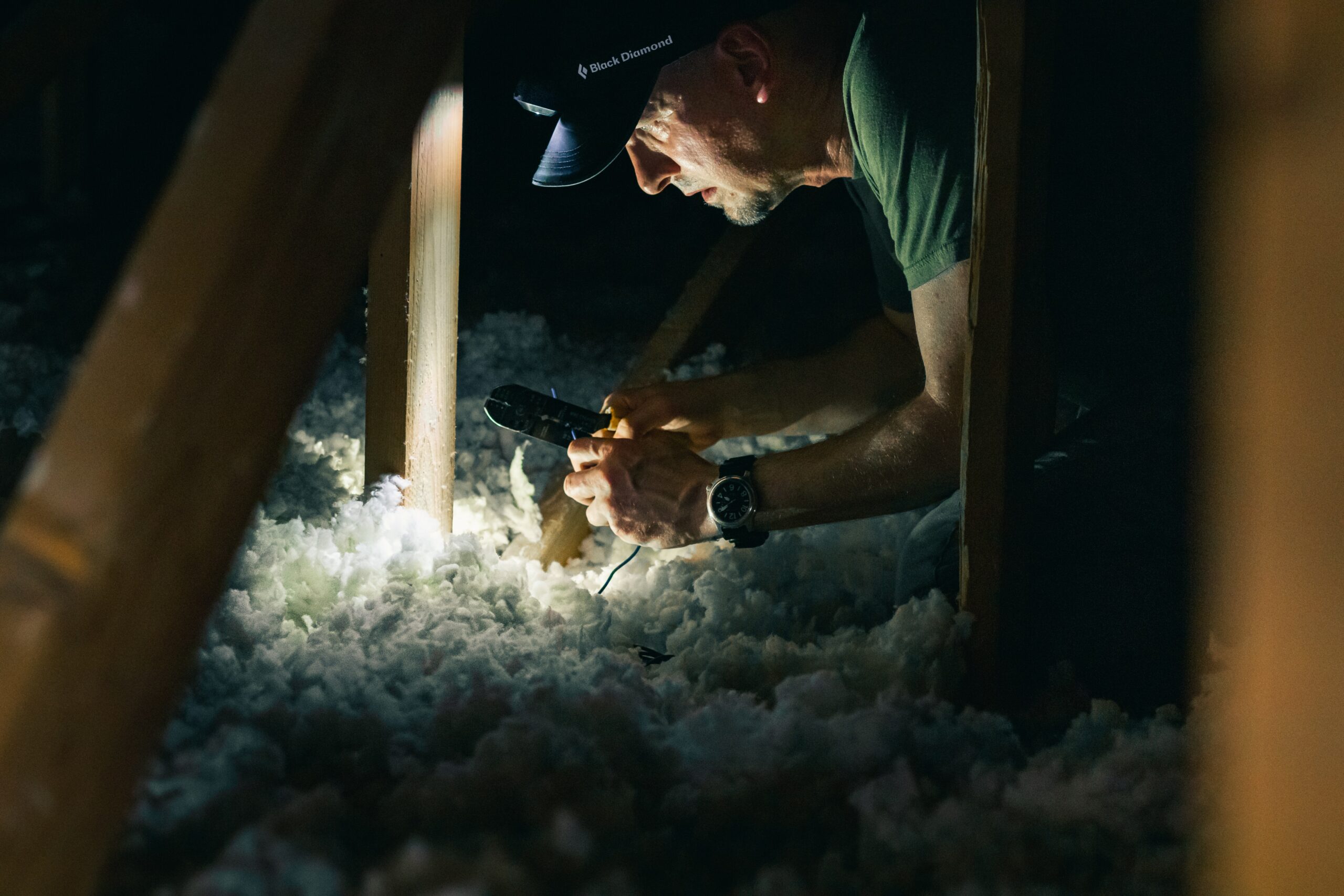 A man inspects the depth of attic insulation